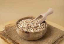 A wooden bowl filled with oats and a wooden scoop