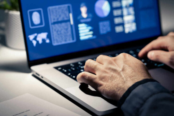 Close-up of hands typing on a laptop with data visualizations on the screen