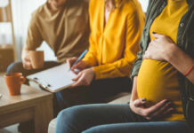 Pregnancy Panic: Are You Taking the Wrong Vitamin? Pregnant woman sitting with two people discussing notes in a cozy living room