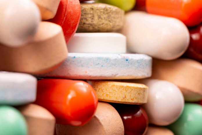 shutterstock_1412813969.jpg A close-up view of a variety of colorful pills and tablets stacked together