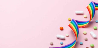 Colorful pills and a rainbow ribbon on a pink background