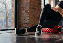 Hip Pain? This Pose Could Save You Person using a foam roller for stretching in a fitness studio
