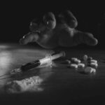 A hand reaching for pills next to a syringe and powder on a table