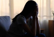 A silhouette of a person sitting with their head in their hands, conveying distress