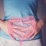 Person holding their stomach with a graphic of intestines overlayed