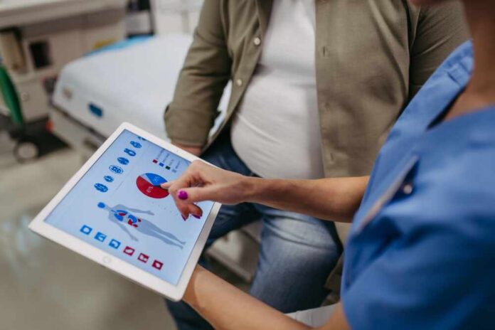 shutterstock_2387615753.jpg Nurse showing a patient health data on a tablet