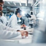 Cancer “Flashlight” Could Change Patient Treatment Forever Scientists working in a laboratory with microscopes and test tubes