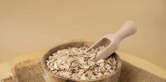 A wooden bowl filled with oats and a wooden scoop