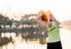 Hormone Shocks Back Pain Treatment Norms A woman stretching her arms by a lake during sunrise