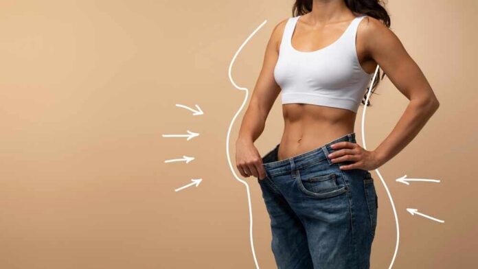 Woman showcasing weight loss by holding oversized jeans