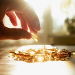 A hand reaching for a golden capsule among many on a table