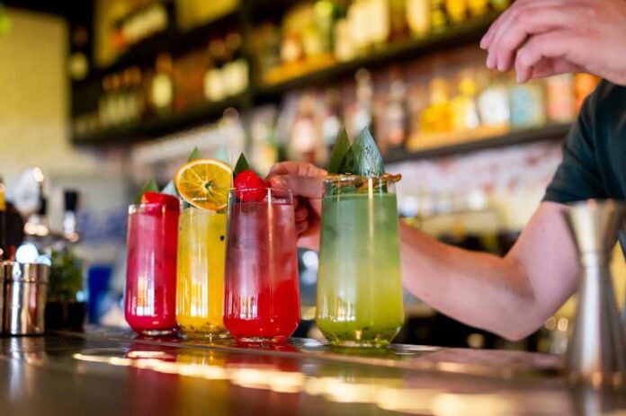 A bartender preparing colorful cocktails at a bar