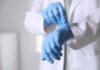 A medical professional putting on blue gloves in a clinical setting