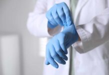A medical professional putting on blue gloves in a clinical setting