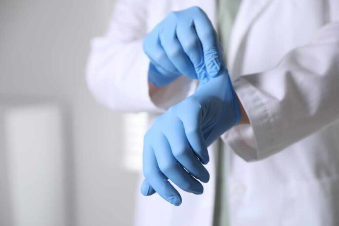 A medical professional putting on blue gloves in a clinical setting