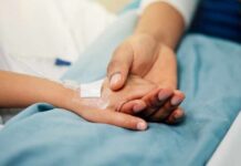 A patient holding hands with a loved one in a hospital setting