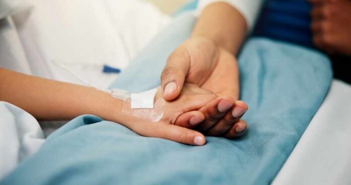 A patient holding hands with a loved one in a hospital setting