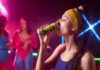Woman in sportswear drinking an energy drink at a vibrant fitness party