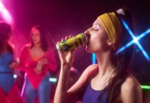 Woman in sportswear drinking an energy drink at a vibrant fitness party