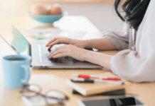 Posture Crisis: Hidden Dangers of Home Offices Person typing on a laptop at a home office desk with a coffee cup nearby