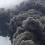Thick dark smoke billowing into the sky