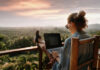 Person working on a laptop outdoors with a scenic sunset view