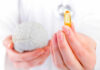 Brain Nutrient Deficit Fueling Anxiety A medical professional holding a brain model in one hand and a yellow supplement capsule in the other
