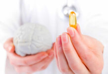 Brain Nutrient Deficit Fueling Anxiety A medical professional holding a brain model in one hand and a yellow supplement capsule in the other