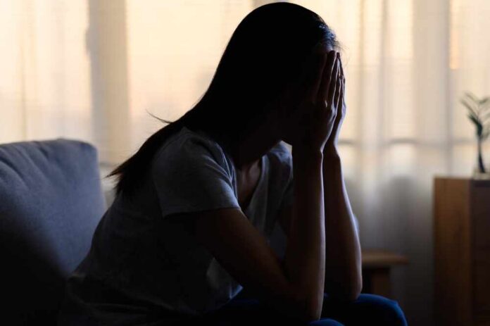 Silhouette,Photo,Of,Young,Asian,Woman,Feeling,Upset,,Sad,,Unhappy A silhouette of a person sitting with their head in their hands, conveying distress