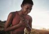 The Best Exercise Sweet Spot For Heart Health A woman in athletic wear holding her chest with a pained expression outdoors