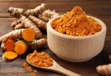 Turmeric’s Power UNLEASHED By This Spice Turmeric powder in a wooden bowl with fresh turmeric roots