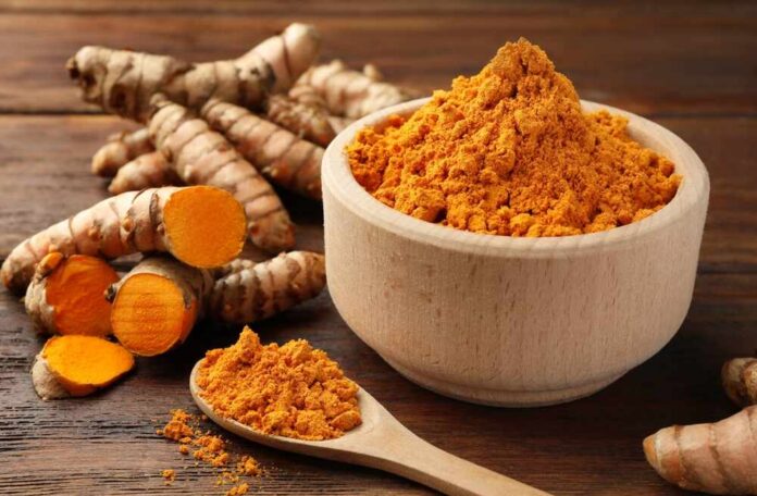 Aromatic,Turmeric,Powder,And,Raw,Roots,On,Wooden,Table,,Closeup Turmeric powder in a wooden bowl with fresh turmeric roots