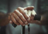Your Aging Clock SLOWED By This Daily Boring Habit Close-up of elderly hands resting on a walking cane