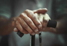 Your Aging Clock SLOWED By This Daily Boring Habit Close-up of elderly hands resting on a walking cane