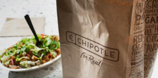 A Chipotle takeout bag next to a bowl filled with fresh salad ingredients