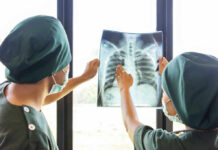 Two medical professionals examining an x-ray of a chest
