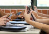 Students in a classroom using smartphones for a group activity