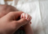 Parenthood’s Hidden Romance Tax A close-up of a babys hand being held by an adult hand