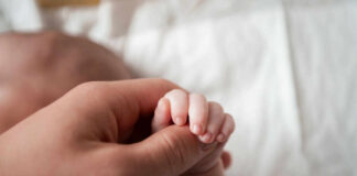 A close-up of a babys hand being held by an adult hand