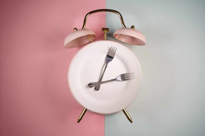 Alarm,Clock,And,A,Plate,With,Fork,And,Knife.,Time An alarm clock with a plate and two forks arranged in a creative design