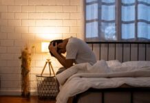 Silent Brain Fog Warnings You Shouldn’t Ignore A person sitting on a bed with their head in their hands, expressing distress