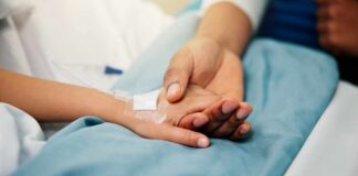 A patient holding hands with a loved one in a hospital setting