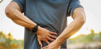 Person holding lower back in pain outdoors