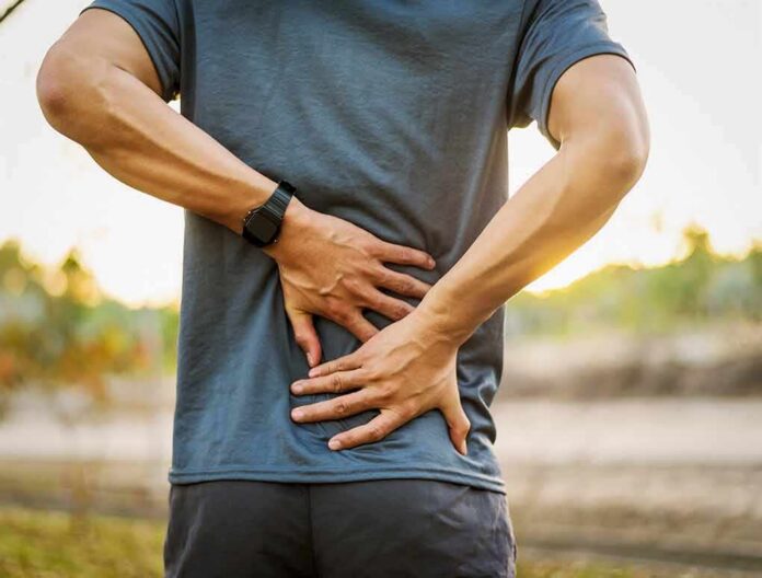 Person holding lower back in pain outdoors