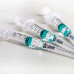 Three syringes filled with blue-green liquid on a white surface