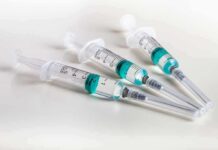 Three syringes filled with blue-green liquid on a white surface