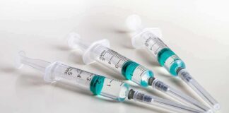 Three syringes filled with blue-green liquid on a white surface