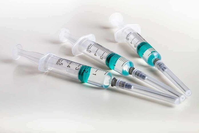 shutterstock_1023268120 Three syringes filled with blue-green liquid on a white surface