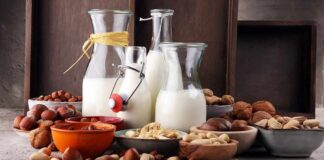 Glass bottles of milk surrounded by assorted nuts in bowls