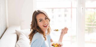 Woman sitting on a couch eating a bowl of fruit salad